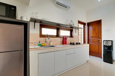 a kitchen with white cabinets and a black refrigerator at Stylish 3BR Villa Sandalwood near Beach in Seminyak