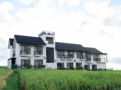 a white building in a field of grass at Jiva Flow Kerobokan in Kerobokan