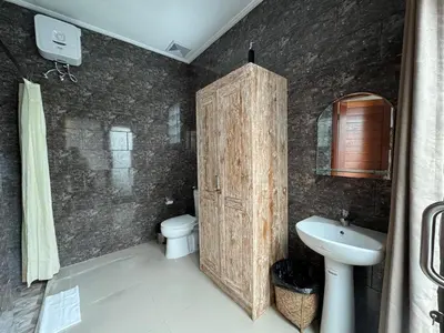 a bathroom with a wooden door and a toilet and a sink at CWB Villa in Kerobokan