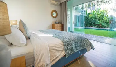 a bedroom with a bed and a large window at Desa Berawa Beach Villa No13 in Canggu