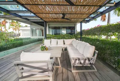 a patio with a wooden table and white chairs at Desa Berawa Beach Villa No13 in Canggu
