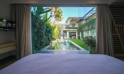 a bedroom with a view of a backyard with a swimming pool at Desa Berawa Beach Villa No13 in Canggu