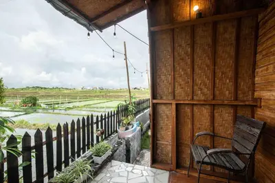 a porch with a chair and a view of a field at Little Farm House Kerobokan near Seminyak in Kerobokan