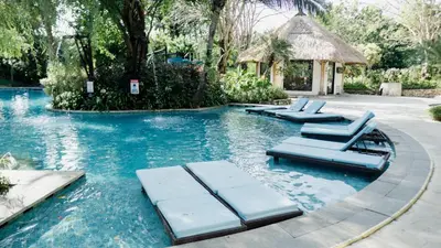 a swimming pool with lounge chairs in the water at Esco Luxe Jimbaran in Jimbaran