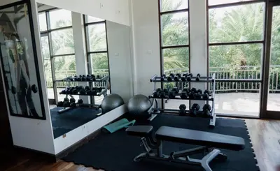 a gym with a lot of equipment and windows at Esco Luxe Jimbaran in Jimbaran
