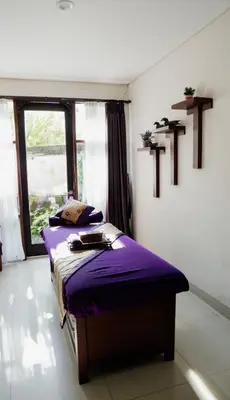 a bedroom with two beds with purple sheets and a window at Esco Luxe Jimbaran in Jimbaran