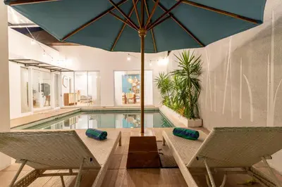 a table with an umbrella next to a swimming pool at Villa Palma Blanca Canggu by Nagisa Bali in Canggu