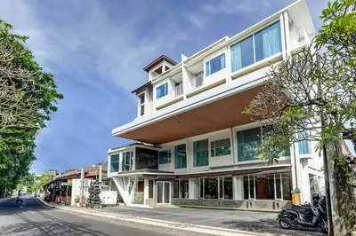 a tall white building with windows on a street at Dancenter Premium Legian Hotel in Balian