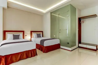a hotel room with two beds and a shower at Dancenter Premium Legian Hotel in Balian