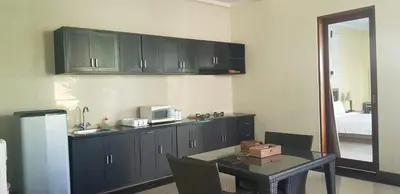 a kitchen with black cabinets and a table with a microwave at Privat Pool Villa with Kitchen at seminyak in Seminyak