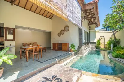 a house with a swimming pool and a table and chairs at Classic Pool villa with kitchen in Seminyak