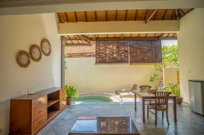 a living room with a table and chairs and a pool at Classic Pool villa with kitchen in Seminyak