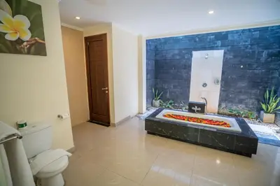 a bathroom with a toilet and a bathtub with flowers in it at 1BR Private Pool Villa in Seminyak PB in Seminyak
