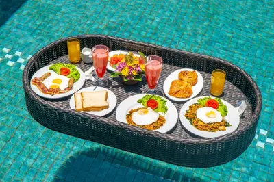a tray of breakfast food on a table in a pool at 1BR Private Pool Villa in Seminyak PB in Seminyak