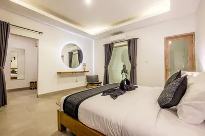 a bedroom with a large white bed and a chair at Harmony Villa Two Bedroom in Canggu