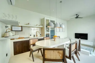 a kitchen with a white table and chairs and a tv at Villa Madame 3BR Villa Private Pool in Berawa in Canggu