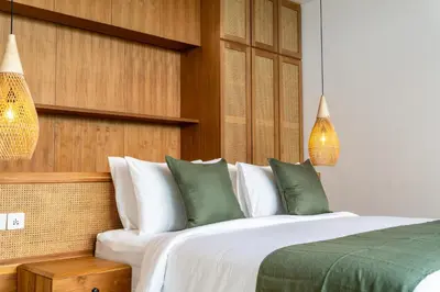 a bedroom with a bed with green and white pillows at Gelareh Villa Berawa in Canggu