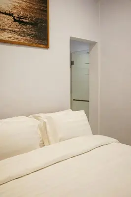 a bed with white sheets and a painting on the wall at Villa Frankie in Central Legian in Legian