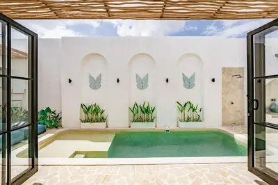 an indoor swimming pool in a house with glass doors at Soft Opening! Villa Lumière 1 Seminyak in Seminyak