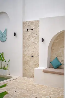 a bathroom with a shower with a stone wall at Soft Opening! Villa Lumière 1 Seminyak in Seminyak