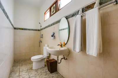 a bathroom with a sink and a toilet and a mirror at Gracia Apartment Seminyak Managed by Manara in Seminyak