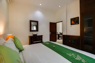 a bedroom with a bed with a green and white blanket at Gracia Apartment Seminyak Managed by Manara in Seminyak