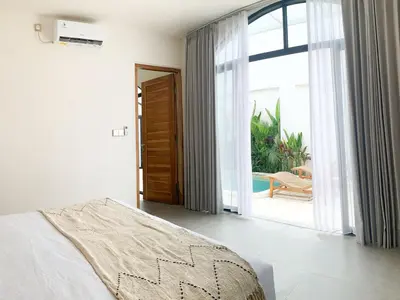 a bedroom with a bed and a sliding glass door at Cozy and Chic Villa with Private Pool at Balangan in Jimbaran