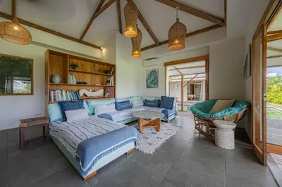 a living room with a blue couch and a table at Villa Rice - Amazing Rice-Field VIEW 3BR Villa 9px Next To Canggu in Kerobokan