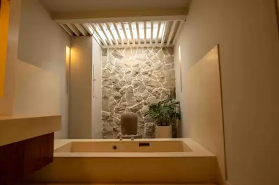 a bathroom with a bath tub with a stone wall at Tuluscolivingseminyakvilla1 in Seminyak
