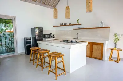 a kitchen with a white counter and stools in it at Villa Vaimala 4BR Pool Tropical Home Seminyak in Seminyak
