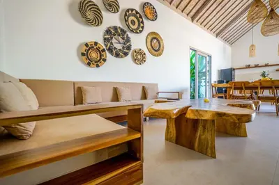 a living room with a couch and a table and plates on the wall at Villa Vaimala 4BR Pool Tropical Home Seminyak in Seminyak