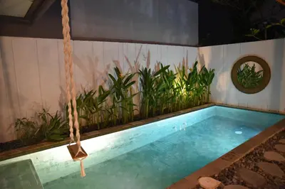a swimming pool with a swing in a room with plants at Casa Nakoa 2BR With Private Pool in Nusa Dua