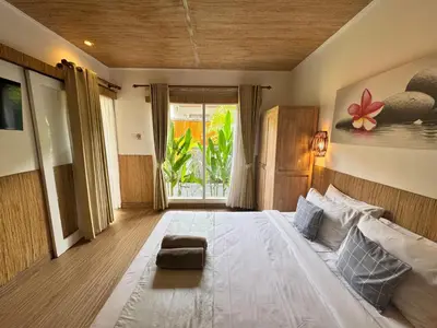 a bedroom with a large white bed and a window at Kubu Betel Home Stay in Canggu