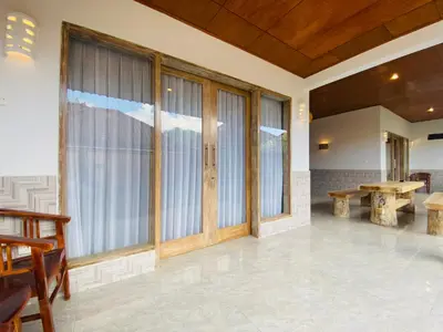 a living room with sliding glass doors and a table at Kubu Betel Home Stay in Canggu