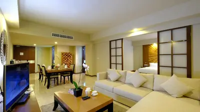 a living room with a couch and a room with a bed at The Sintesa Jimbaran Bali in Jimbaran