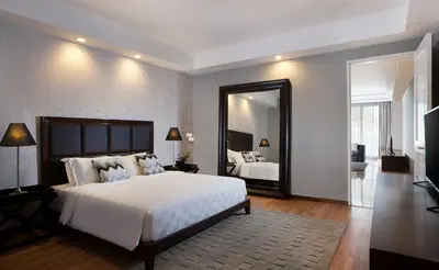 a bedroom with a large white bed and a mirror at The Sintesa Jimbaran Bali in Jimbaran