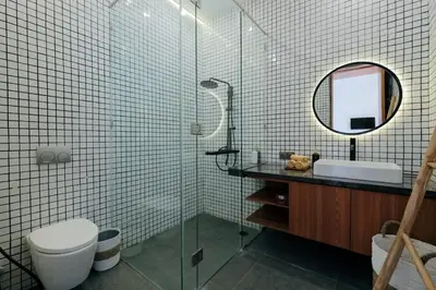 a bathroom with a glass shower with a toilet and a mirror at Anama Villa Kerobokan in Seminyak