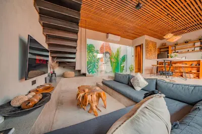 a living room with a blue couch and a table at Villa Cek Ombak 2 Canggu in Canggu