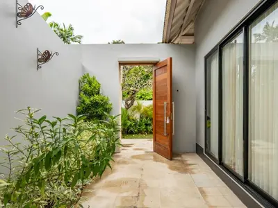 a hallway with a door and some plants at tuluscolivingseminyakvilla3 in Seminyak