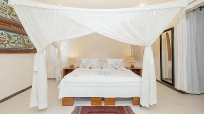 a bedroom with a white bed with a canopy at Gembira Villa Seminyak in Canggu