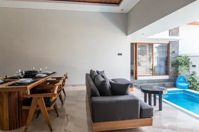 a living room with a dining table and a swimming pool at Villa Sakura III Seminyak in Seminyak