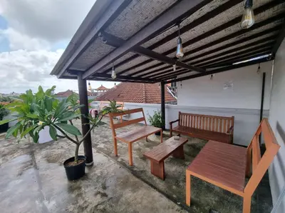 a patio with benches and a table and a potted plant at RBE Hotel Kuta 2- 5 Min to Airport&Beach by Micky Studio in Ngurah Rai International Airport