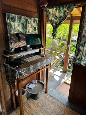 a desk with a computer in a room with a window at Desa Biasa in Kerobokan