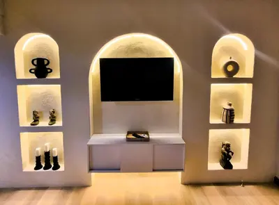a tv in a room with two arched windows at Mana Suites Bali in Kuta