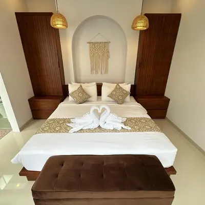 a bedroom with a bed with two white sheets at Maithala Villa & Living in Kuta