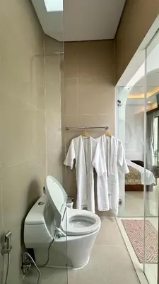 a bathroom with a toilet and towels on a wall at Maithala Villa & Living in Kuta