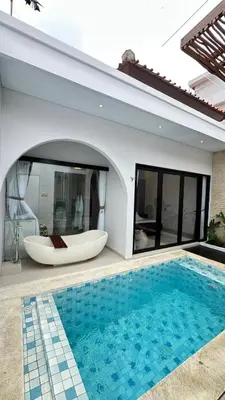 a bath tub sitting next to a house with a swimming pool at Maithala Villa & Living in Kuta
