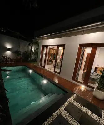 a swimming pool in front of a house at night at Villa Dharman Jimbaran in Jimbaran