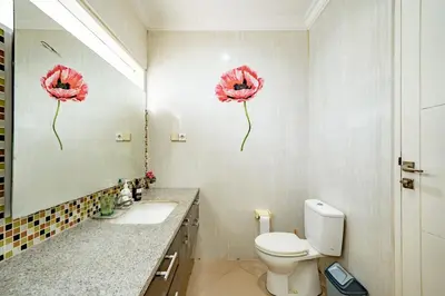 a bathroom with a toilet and a mirror with flowers on the wall at Casa Raya 4BR Villa in Kuta in Kuta