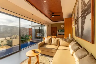 a living room with a couch and a large window at Villa Sattvika in Kerobokan